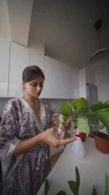 Güzel bir bornoz giymiş bir kadın ev bitkileriyle ilgilenir. Bahçe işlerinin güzelliğini gösterir.