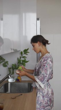 Bir kadın, şık mutfağında günlük mutfak ritüellerini kucaklayan taze malzemeler hazırlar..