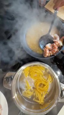 Harika bir aşçılık sahnesi makarna ve karidesin ustalıkla pişirildiği bir soba tepesinde.