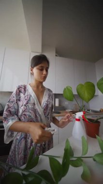 Bir kadın canlı kapalı salonda bitkileriyle ilgilenir. Güzellik ve sükunetle dolu yemyeşil bir ortam sunar.