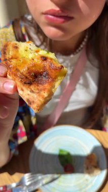 Genç bir kadın arkadaşlarıyla güneşli bir açık hava ortamının tadını çıkarırken lezzetli bir dilim pizzanın tadını çıkarıyor.
