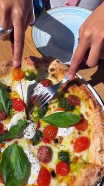 Lezzetli ve ağız sulandıran taze fesleğenli, olgun domatesli ve kremalı burrata peynirli bir pizza.