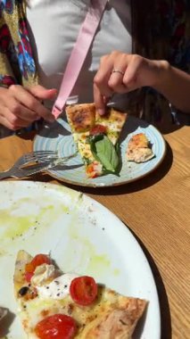 İki arkadaş taze fesleğen ve domatesli lezzetli ve lezzetli pizzanın tadını çıkarıyor.