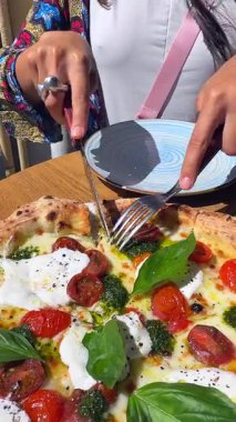 Taze fesleğen, kiraz domatesleri ve kremalı mozarelladan oluşan lezzetli bir pizzanın tadını çıkarın. Tüm yemek severler için mükemmel.