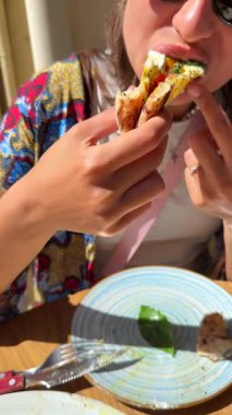 Lezzetli bir sahne, doğada dinlenirken lezzetli bir sandviçin tadını çıkaran bir kadını tasvir eder.