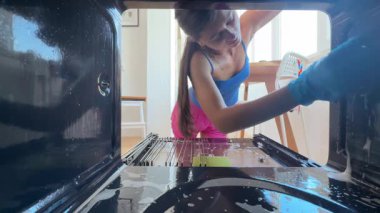 Bir kişi fırını etkin bir şekilde temizliyor, çeşitli teknikleri dikkatlice ve detaylara dikkat ederek sergiliyor.