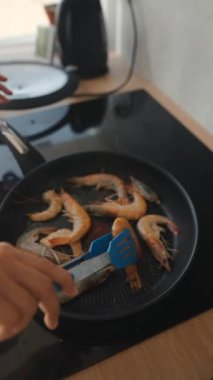 Çağdaş bir mutfak ortamında spatulayla sotelenen lezzetli karidesler.