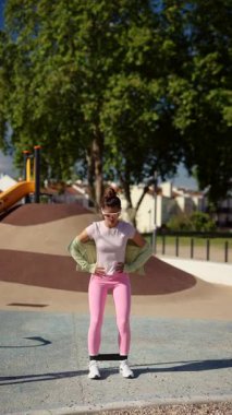 Renkli aktif giyimli canlı ve şık bir figür açık hava parkındaki neşeli bir ortamda enerjik bir şekilde poz veriyor.