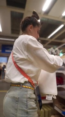 Bir kişi, etrafındaki çeşitli ürünlerle uğraşırken tesadüfen bir mağazada dolaşır ve alışveriş yapar.