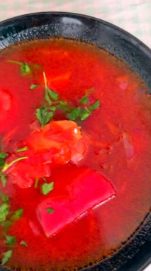 Lezzetli bir çorba, taze ekmek ve ahşap bir tahtanın üzerinde çeşitli malzemelerle servis edilir.