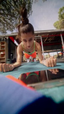 Kendini adamış genç bir kadın açık havada ahşap bir antrenmana katılıyor. Kararlılığını ve zindeliğini açıkça gösteriyor.