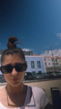 Şık bir genç kadın, gün boyunca canlı bir şehir manzarasında kamerasıyla güzel anları yakalar.