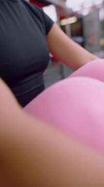 Şık jimnastik kıyafetleri içinde odaklanmış bir kadın yoğun bir şekilde spor yapıyor. Forma ve sağlığa olan bağlılığını vurguluyor.