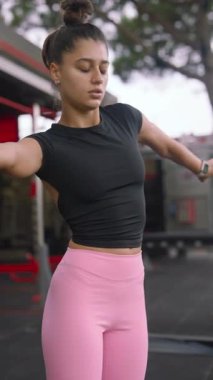 Genç bir kadın coşkulu bir şekilde hareketli ve hareketli bir spor salonu atmosferinde dinamik esnemeler sergiliyor.