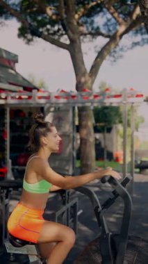 Formda genç bir kadın dışarıda bisiklet sürüyor. Manzaralı yolda giderken zindeliğini ve enerjisini gösteriyor.