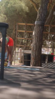 Kendini işine adamış genç bir kadın doğada renkli direniş bantlarıyla egzersiz rutinleri sergiliyor.