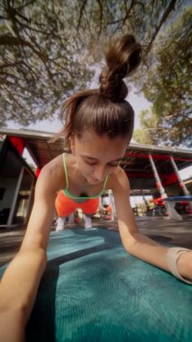 Huzurlu bir parkta, kendini adamış bir kadın zorlu bir tahta egzersizi yapar, spor yapmaya olan bağlılığını gösterir.