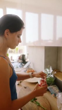 Güzel dizayn edilmiş mutfak ortamında, taze ve canlı malzemeleri ustaca hazırlayan bir kadın.