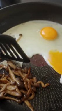 Lezzetli yumurta ve mantarlar sıcak tavada cızırdıyor. Besleyici bir kahvaltı için mükemmel.