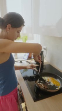 Genç bir kadın şık ve modern bir mutfak ortamında lezzetli yumurtalar pişirir.