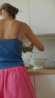 Güzel aydınlatılmış bir mutfakta, bir kadın besleyici bir yemek için taze ve canlı sebzeler hazırlıyor.