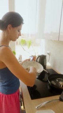 Bir kadın parlak bir mutfakta ustalıkla yemek hazırlar. Mutfak yaratıcılığı ve sağlıklı tercihler sunar..