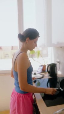 Parlak ve havadar bir mutfakta ustalıkla yemek pişiren bir kadın, tamamen odaklanmış ve aşçılık görevine odaklanmış.