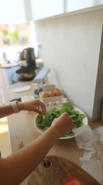 Bir birey, modern ve şık bir mutfak ortamında taze ve canlı salata malzemeleri hazırlıyor.