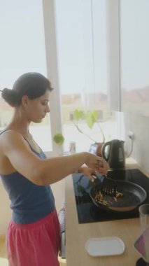 Güneşli bir mutfakta, bir kadın ustalıkla yemek pişirir, sağlıklı yaşam tarzını ve etkileyici mutfak becerilerini gösterir.