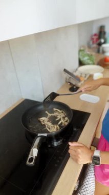 Canlı bir yemek sahnesi, mantarların sıcak bir tavada cızırdadığını gösteriyor. Mutfak yaratıcılığını ve becerisini ön plana çıkarıyor.