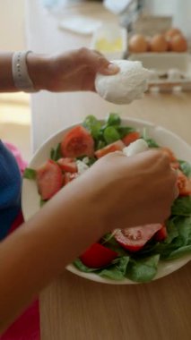 Mozarella ve sulu domateslerin yer aldığı taze ve renkli bir salatayı ustaca hazırlayan ellerin yakın çekimi.