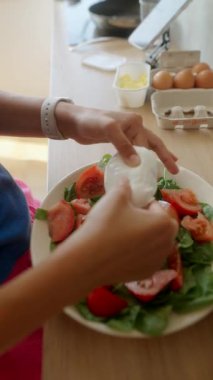 Olgun domatesler, ıspanak ve krem peynirden oluşan taze ve canlı bir salatayı dikkatlice bir araya getiren el.