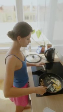 Parlak bir mutfakta, genç bir kadın modern yemek teknikleri ve stilleri kullanarak lezzetli bir yemek hazırlıyor.