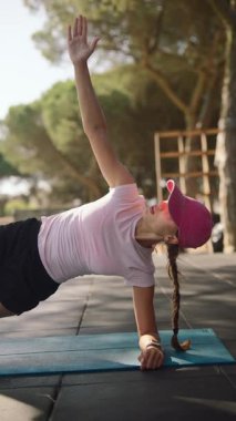 Bir atlet, güzel bir açık hava ortamının dinginliğinin tadını çıkararak, çekirdek güçlendirici bir egzersize girişir.