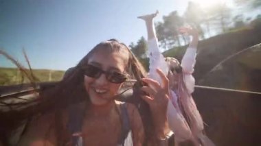 İki kaygısız arkadaş güneşli bir günde şık bir üstü açık arabayla ferahlatıcı bir yolculuğun tadını çıkarıyorlar.