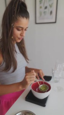 Canlı bir mutfak ortamında, yetenekli genç bir kadın ustaca bir dizi taze malzeme hazırlar.