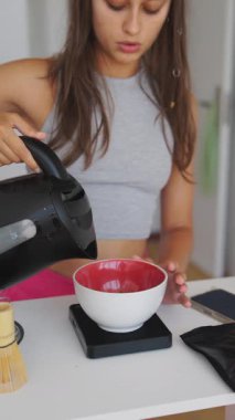 Sakin ve dingin bir insan çay içmek için sıcak suyu bir kaseye döker. Huzurlu bir mutfak atmosferi sergiler.