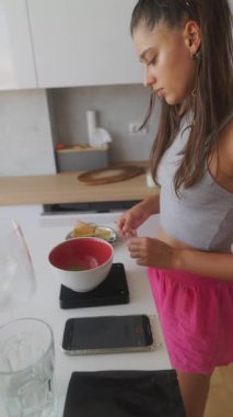 Genç bir kadın modern bir mutfakta heyecan verici bir mutfak macerası için çeşitli malzemeler hazırlıyor.