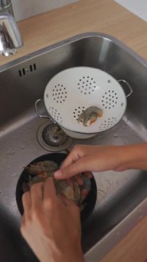 Bir insan lavabodaki taze karidesleri titizlikle temizler, onları lezzetli ve lezzetli bir yemek için hazırlar.