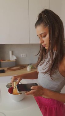 Genç bir insan lezzetli bir yemek hazırlarken akıllı telefonu yemek tarifi için kullanır.