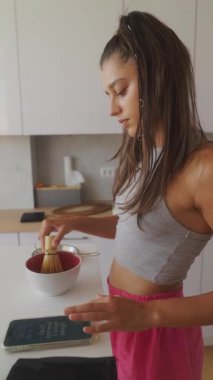 Modern ve şık bir mutfakta, genç bir kadın çeşitli malzemeleri karıştırıyor, mutfak yaratıcılığını sergiliyor.