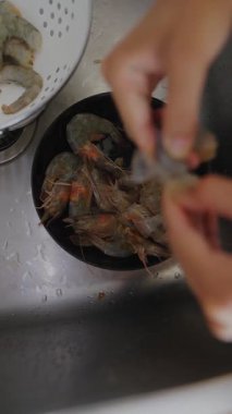 Büyük bir dikkatle, eller titizlikle temizler ve karidesleri mutfak lavabosunda pişirir.