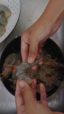 Elleri kabın içinde karides temizliyor, deniz ürünlerini lezzetli yemekler için hazırlıyor hevesli lokantalar tadını çıkarmaya hazır.