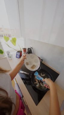 Canlı bir mutfak sahnesi şık bir tavada taze karides pişirme sürecini gözler önüne seriyor.