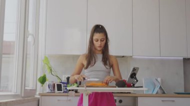 Genç bir kadın, parlak ve modern bir mutfak ortamında taze, canlı malzemeler hazırlıyor.