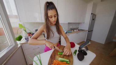 Yetenekli bir kadın parlak, modern bir mutfak alanında çeşitli taze ve renkli sebzeleri ustalıkla doğruyor.