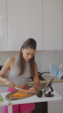 Bir kadın neşeli bir şekilde modern bir mutfakta taze, renkli sebzeler hazırlar, sağlıklı yemek yapma alışkanlıkları sergiler.