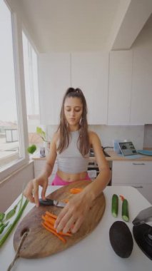 Parlak bir mutfakta, genç bir kadın ustalıkla çeşitli taze sebzeleri büyük bir dikkatle doğruyor.