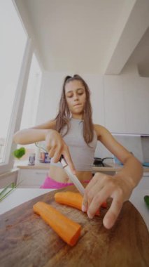Havuçları ustalıkla doğrayan genç bir kadın şık bir mutfakta, aşçılık becerilerini ve tazeliğini sergiliyor..
