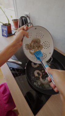 Canlı bir mutfak sahnesi karidesin modern ortamdaki süzgeç ve spatulayla ustalıkla pişirildiğini gösteriyor.